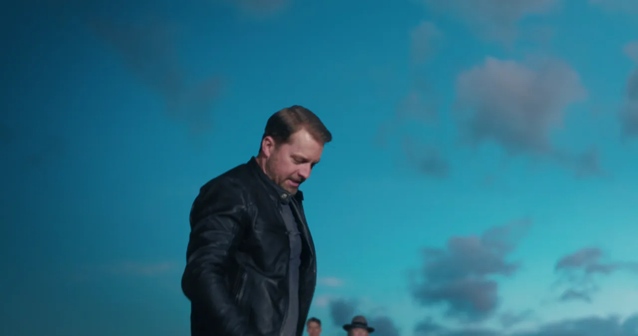 Dot Conner — a man steps off an airport tug against a dusk sky, the finished frame
