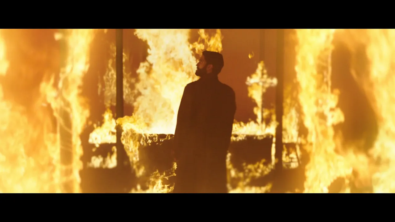 Testament — a figure silhouetted in a doorway wall of fire